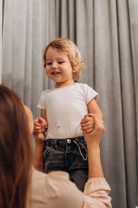Portrait of young woman standing against curtain