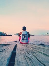 Rear view of man on pier at sea against sky