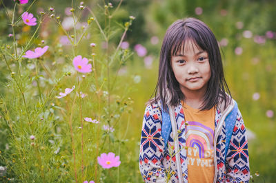 Portrait of young woman standing amidst plants