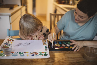 Mother and daughter painting at table