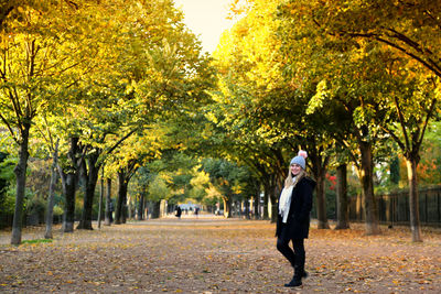 Full length of woman standing on road during autumn