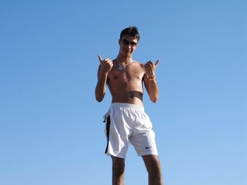 Portrait of young man standing against clear blue sky