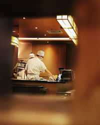 Rear view of man working on table in restaurant