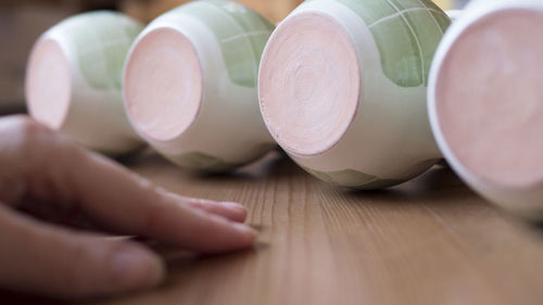 Close-up of human hand by earthenware on table