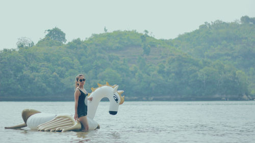 Woman and son on lake against trees