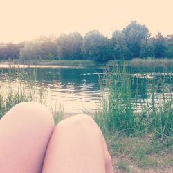 Low section of woman on lake against trees