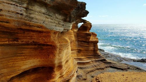 Rock formation and sea against sky