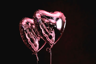 Close-up of heart shape over glass against black background