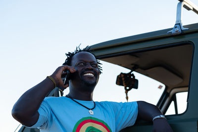 Middle aged black man smiling talking on the phone in his green campin