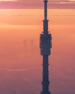 Aerial shot of silhouette ostankino tower in moscow against orange sky during foggy sunrise