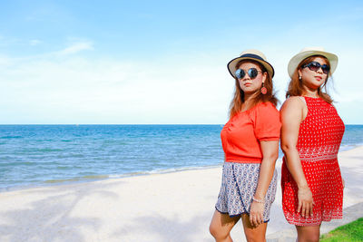 Young woman wearing sunglasses on beach against sky
