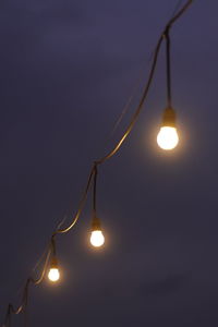 Low angle view of illuminated light bulb against sky