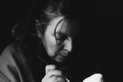 Close-up of woman painting against black background