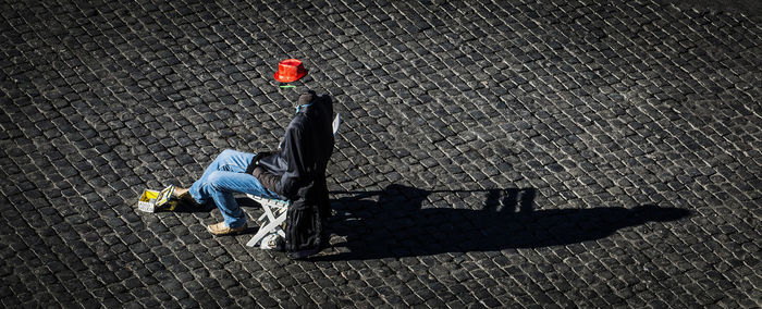 High angle view of man sitting on street