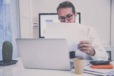 Business man works with laptop sitting at the desk. male at computer work online with remote office