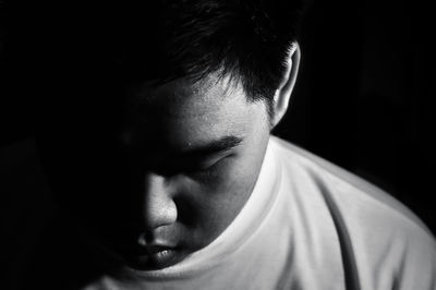 Close-up of boy looking down against black background