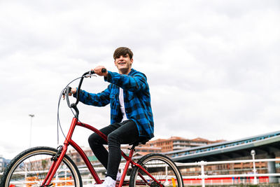 Full length of man riding bicycle against sky