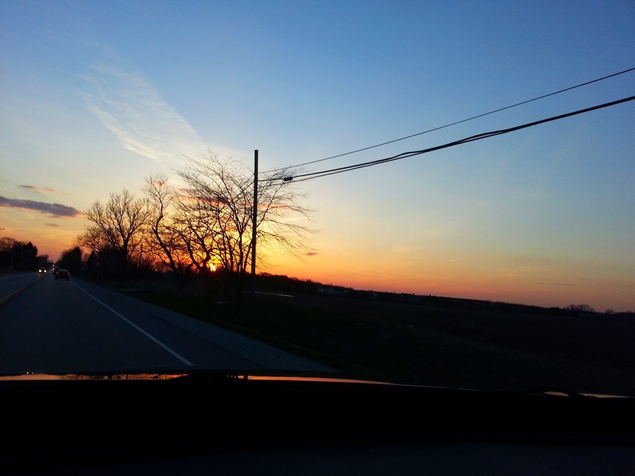 transportation, sunset, road, silhouette, tree, sky, landscape, the way forward, car, country road, land vehicle, mode of transport, tranquil scene, tranquility, diminishing perspective, scenics, clear sky, nature, road marking, electricity pylon