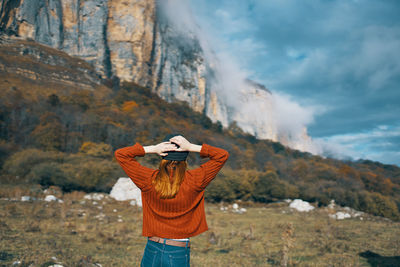 Rear view of woman standing against mountain range