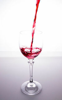 Close-up of wineglass on glass against white background