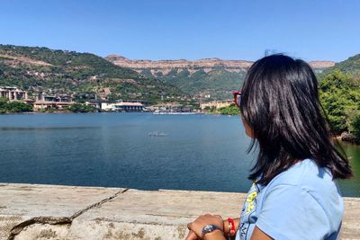 Rear view of woman looking at sea against mountains