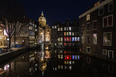 Canal amidst buildings in city at night