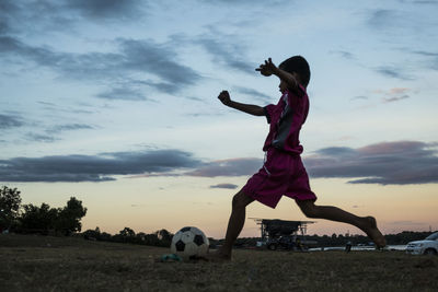 Full length of child playing soccer on field against sky