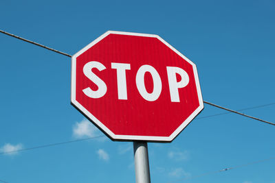 Low angle view of road sign against blue sky