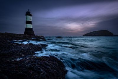 Lighthouse by sea against sky