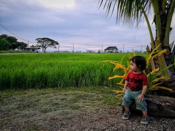 Boy playing on grass against sky