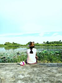 Woman sitting on field against sky
