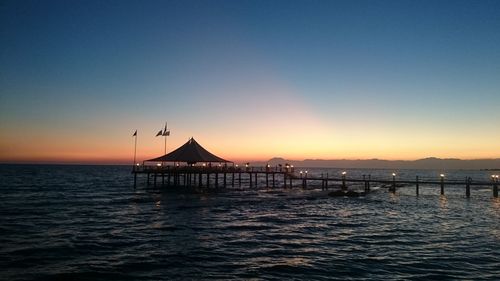 Silhouette pier over sea against clear sky during sunset