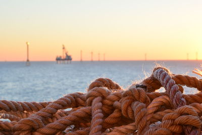 Close-up of rope tied to pier at harbor against clear sky