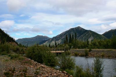 Scenic view of stream and mountains against sky