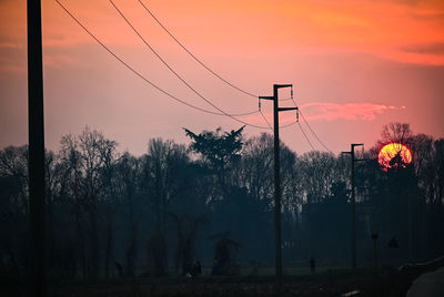 Silhouette trees on field against sky during sunset