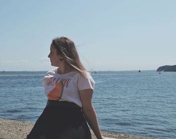 Woman standing at beach against sky