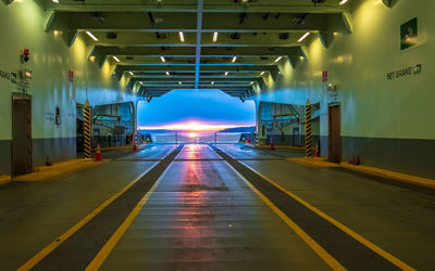 Empty road along illuminated lights