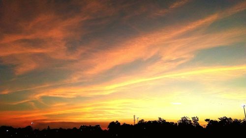 Low angle view of silhouette trees against dramatic sky