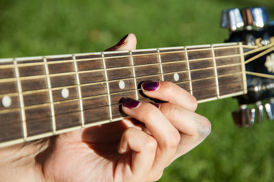 Cropped hand of woman playing guitar at public park