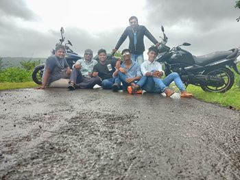 People sitting on motorcycle against sky