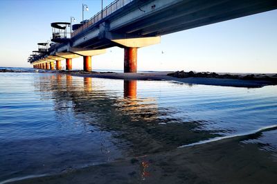 Reflection of bridge on sea against sky