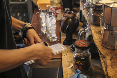 Midsection of people in glass jar on table