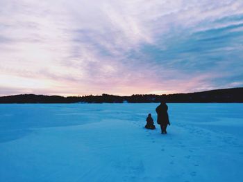 Rear view of silhouette man on snow covered landscape