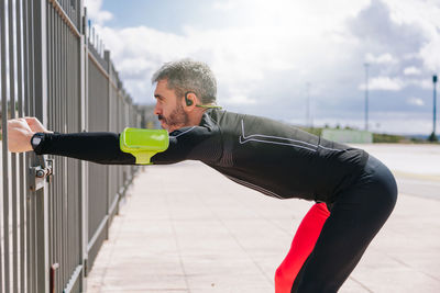 Side view of mature man stretching outdoors