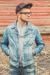 Young man wearing hat standing against brick wall