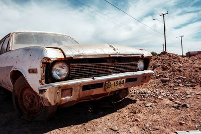 Abandoned car on field against sky