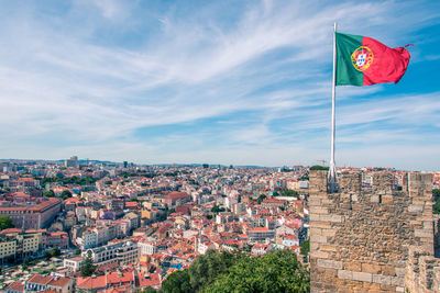 Flag waving on wall against sky in city