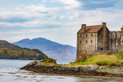 Old building by sea against sky