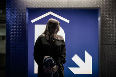 Woman standing against information sign