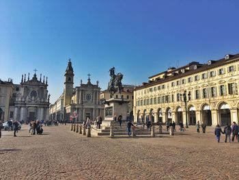 Tourists in front of historic building against clear sky